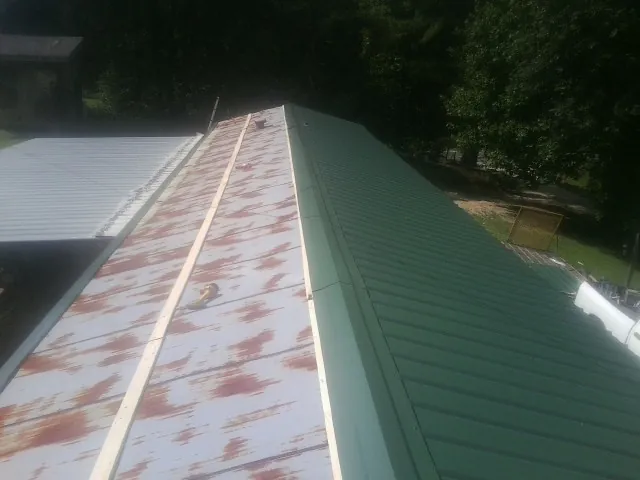 Old rusted panels beside newly installed green metal roofing — Wind Damage Roof Repair by Roofing Brothers in Brackenridge