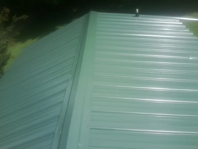 New green metal panels meeting at the ridge of a roof — Flat Roof Repair work by our crew in Brackenridge