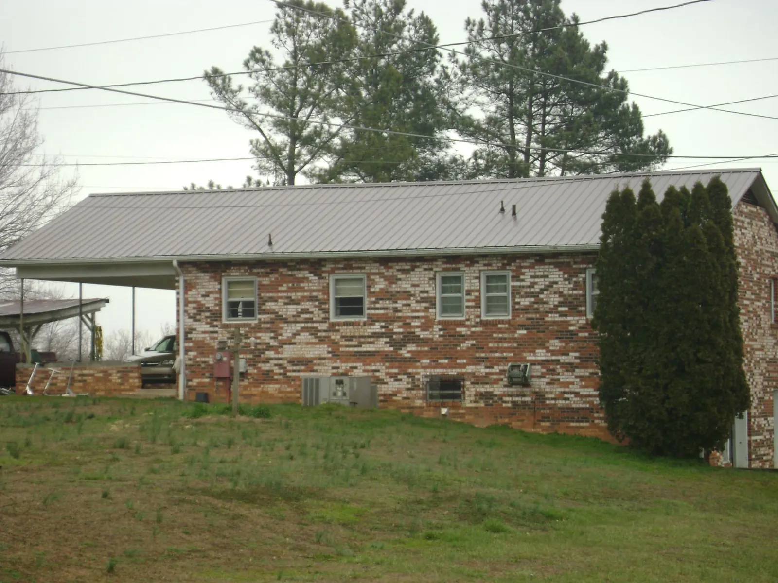 Gray metal roof on a brick split level home with a carport in Brackenridge