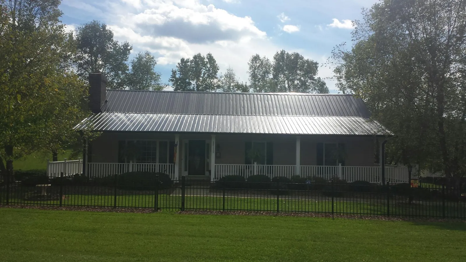Gray metal roof on a brick ranch with a full width front porch — Gutter Guard Installation work by our crew in Brackenridge
