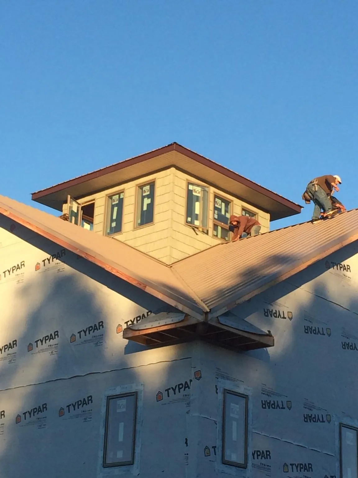 Roofers working around a rooftop cupola on a new metal roof at sunset — Roof Waterproofing in Brackenridge by Roofing Brothers